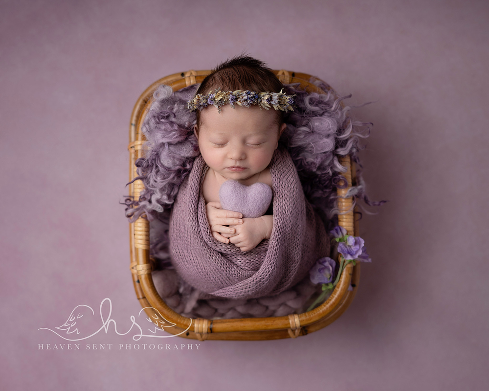 BABY WITH FLOWERS IN HAIR on a purple background by newborn photographer in Guildford, Surrey