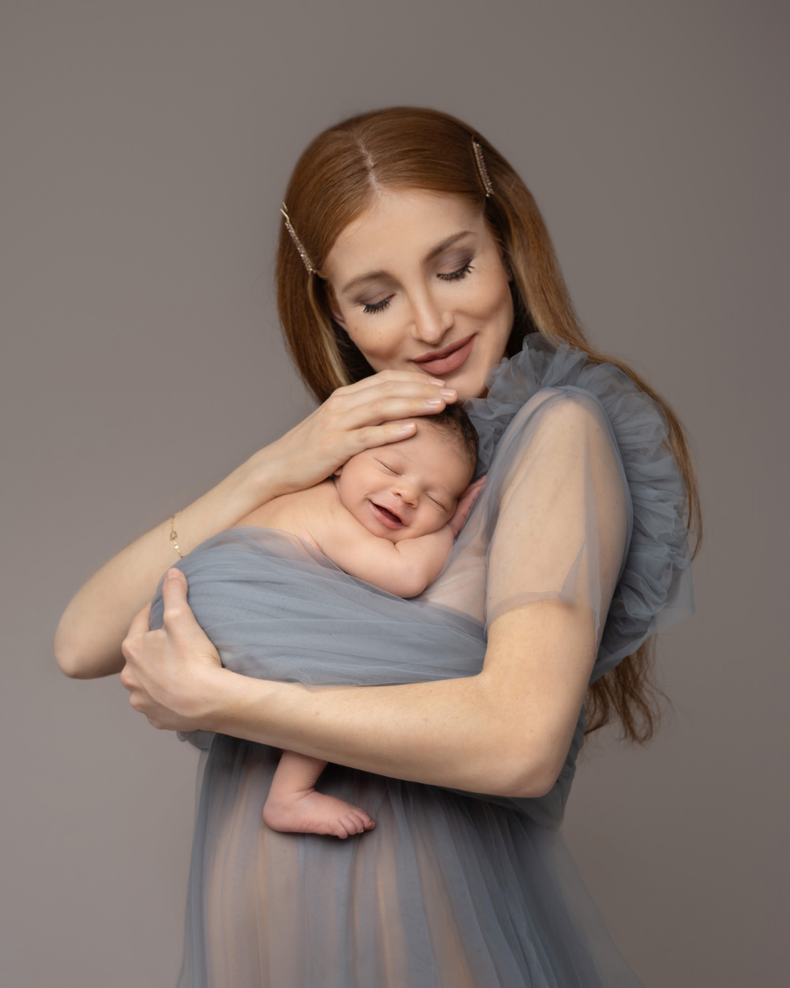 mum with blue dress on cradling newborn baby by newborn photographer in Guildford, Surrey
