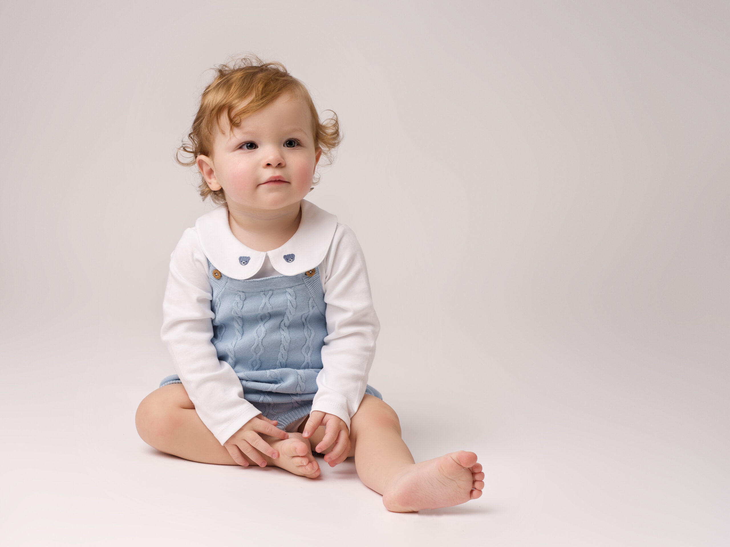 baby in blue sitting at 6 months old by BABY & FAMILY PHOTOGRAPHER IN SURREY