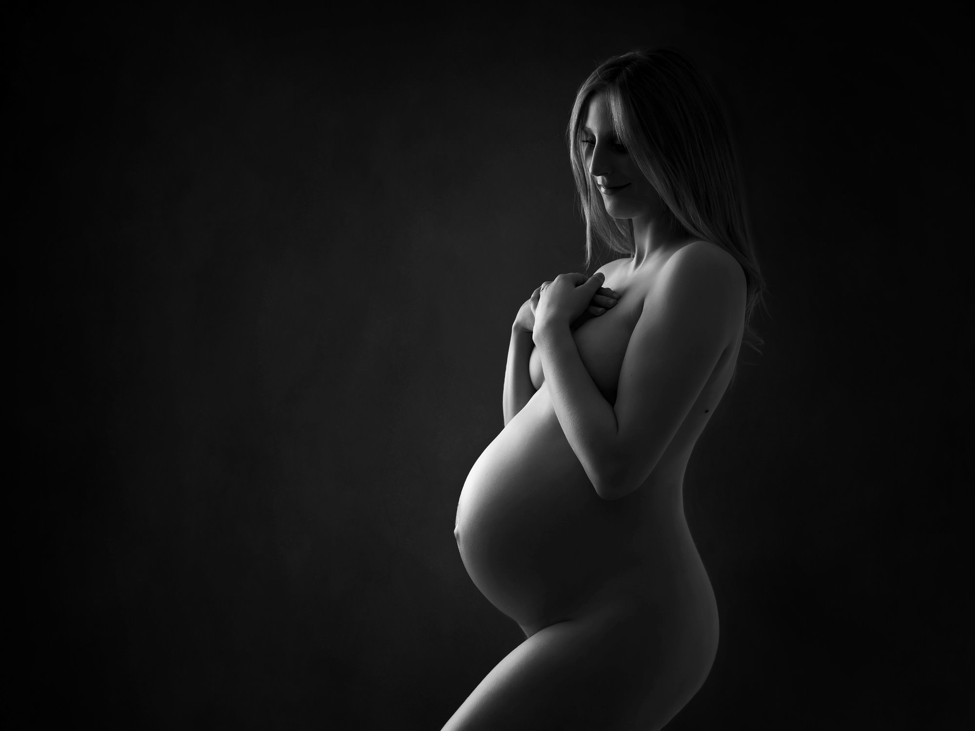 Pregnant lady in silhouette against a black background by maternity photographer in Surrey